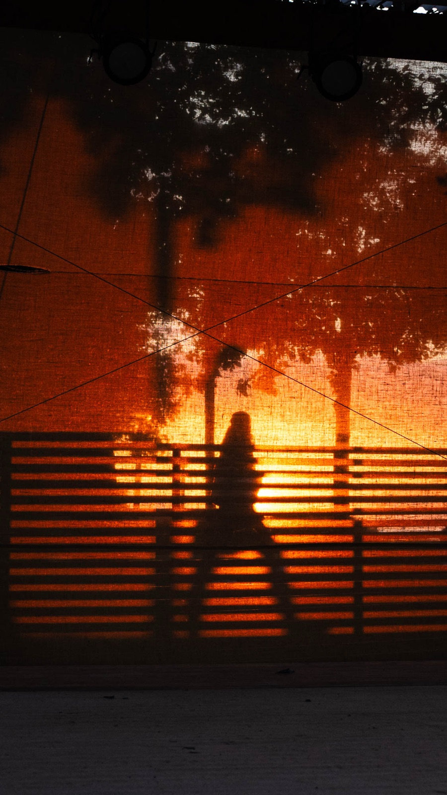 Silhouette of a passer-by behind a sunlit orange weave