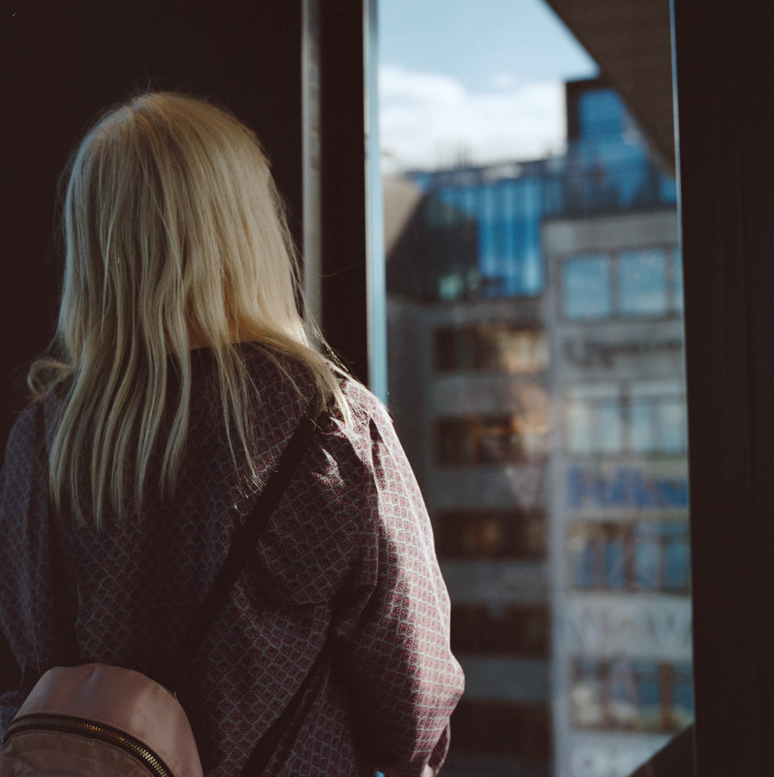Woman at a window looking out over the city, shot on film